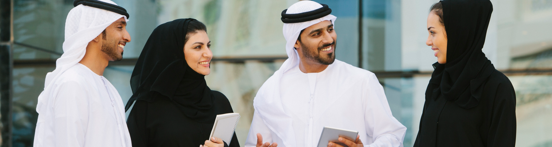 Four arab businesspeople in traditional clothing having a discussion in front of a  office building.