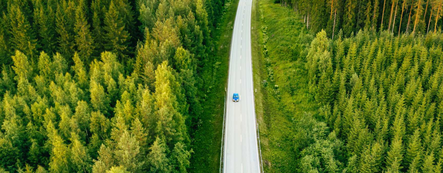 Aerial view from above of country road through the green summer forest in summer Finland. drone photography