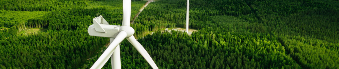 Aerial view of windmills in green summer forest in Finland. Wind turbines for electric power with clean and Renewable Energy