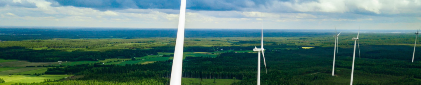 Aerial view of windmills in green summer forest in Finland. Wind turbines for electric power with clean and Renewable Energy
