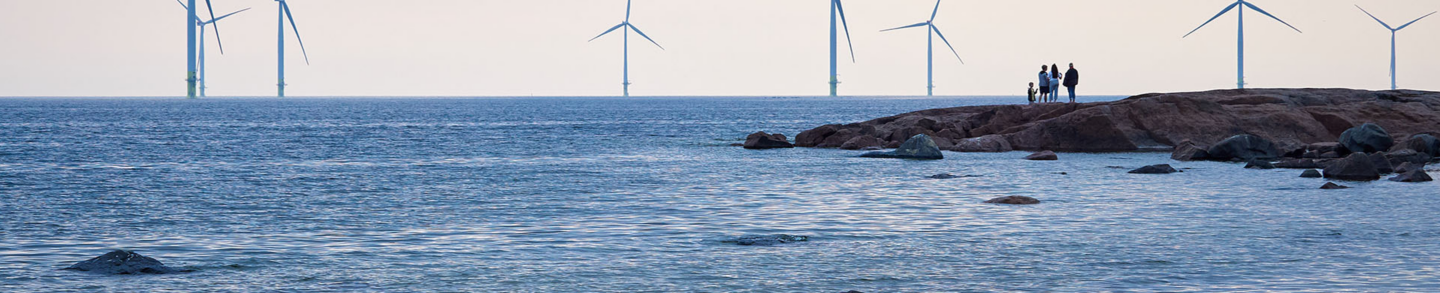 People watching wind mill power generator farm for renewable energy production along coast of Finland.