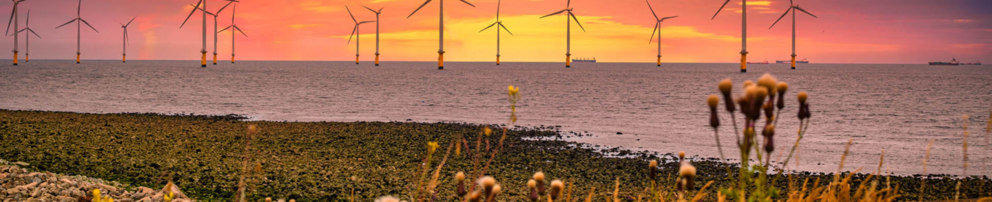 Offshore Wind Turbine in a Wind farm under construction off the England coast at sunset